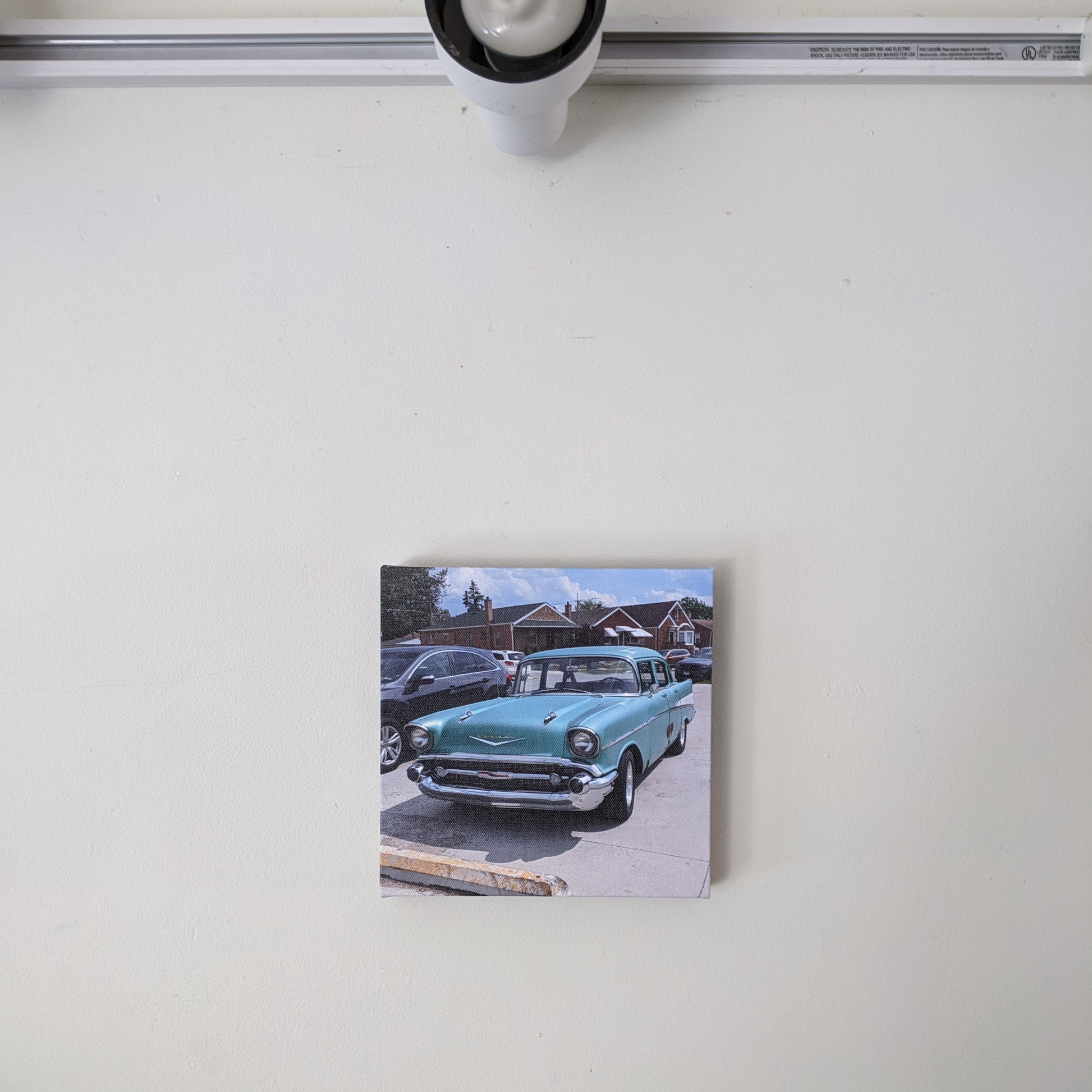 Square canvas print of a 1957 Chevrolet Bel Air, great for home or office décor in a Classic car themed room. Displayed on an off-white wall.